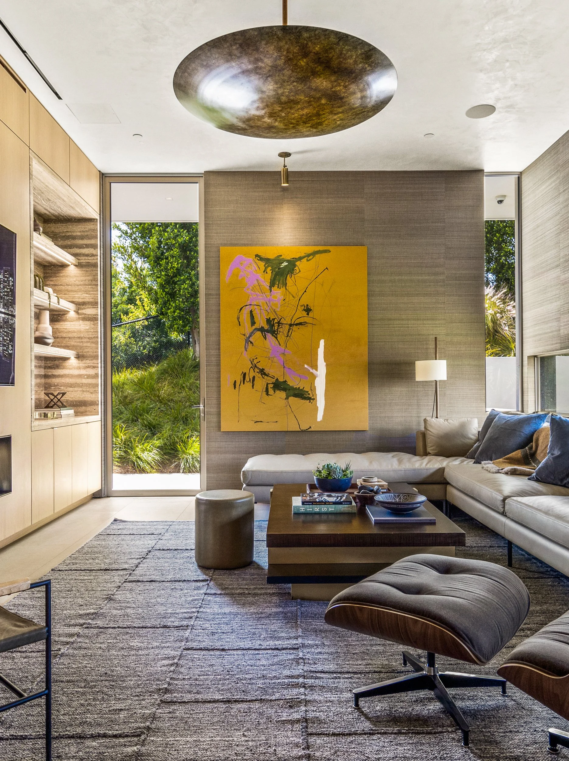 Living room with a large yellow abstract painting on a textured wall and a garden door beyond.